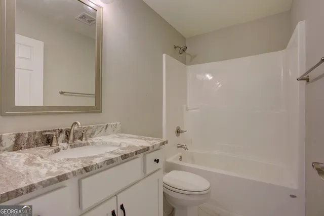 a bathroom with a granite countertop sink a toilet and shower