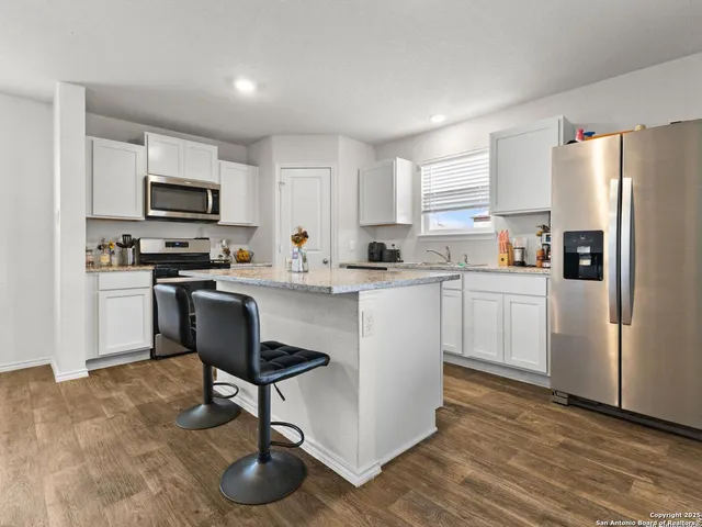 a kitchen with stainless steel appliances a stove a sink a refrigerator a microwave and cabinets