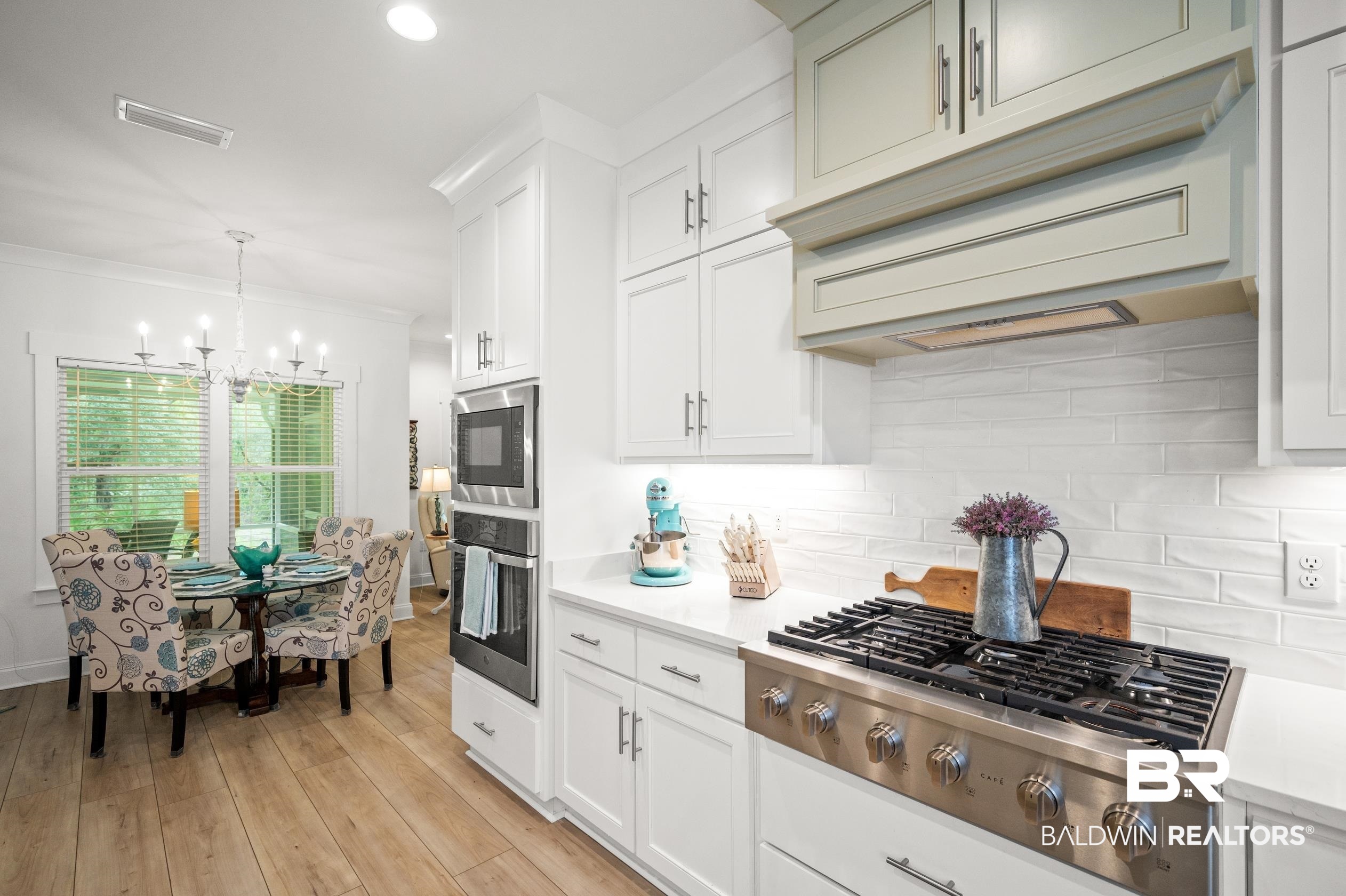 4601 Surrey Lane Orange Beach, AL 36561 - Photo 16 of 43 Kitchen with light wood-type flooring, a notable chandelier, decorative light fixtures, stainless steel appliances, and decorative backsplash