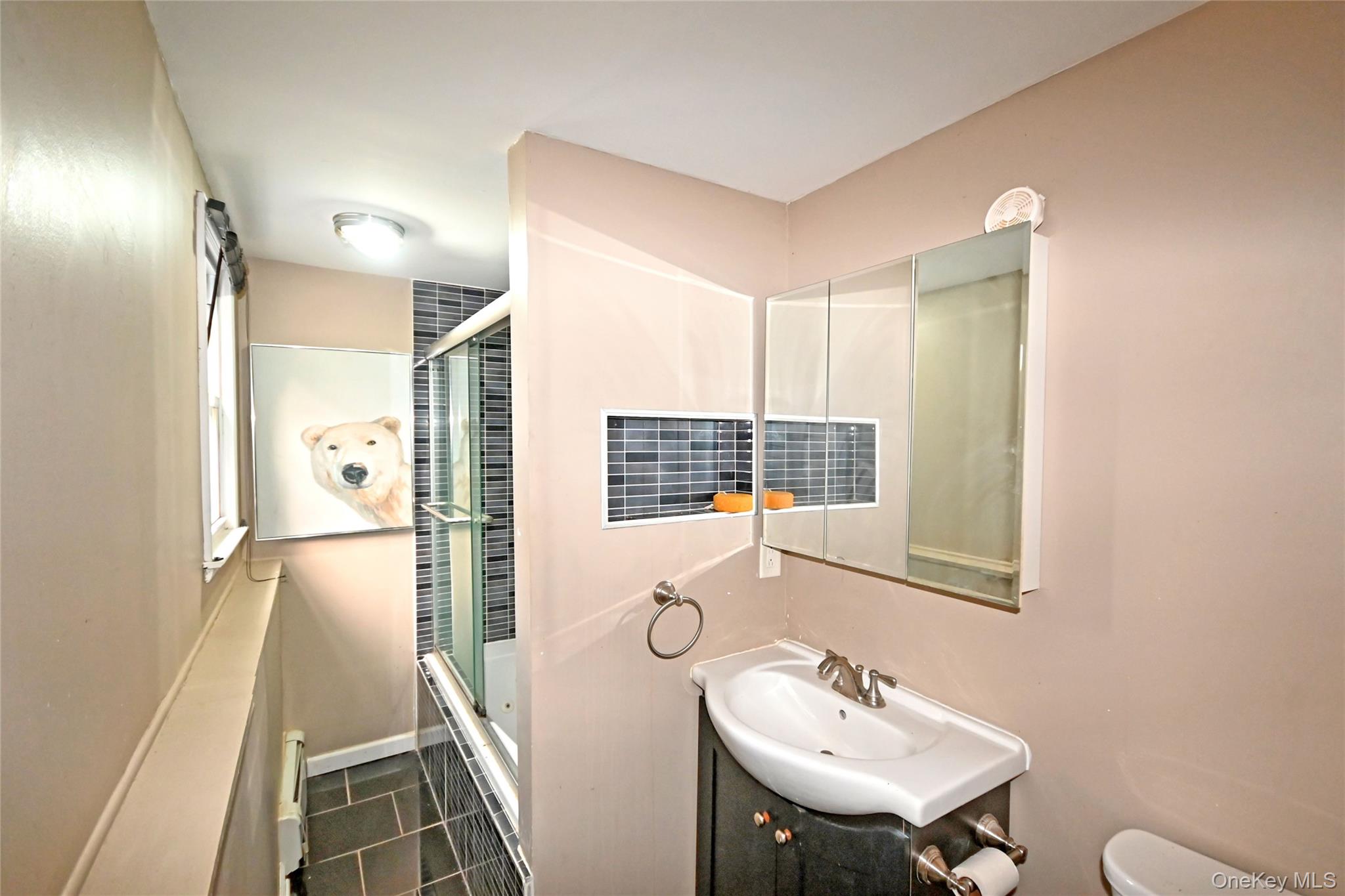 89 Osborne Road West Hempstead, NY 11552 - Photo 39 of 50 Bathroom featuring dark tile patterned flooring, bath / shower combo with glass door, and vanity