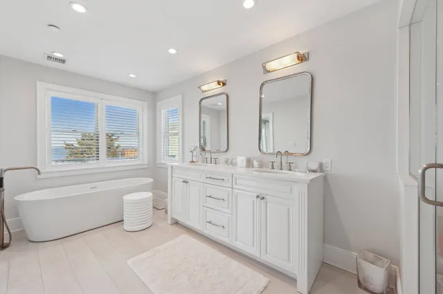 a spacious bathroom with a double vanity sink a mirror and a bathtub