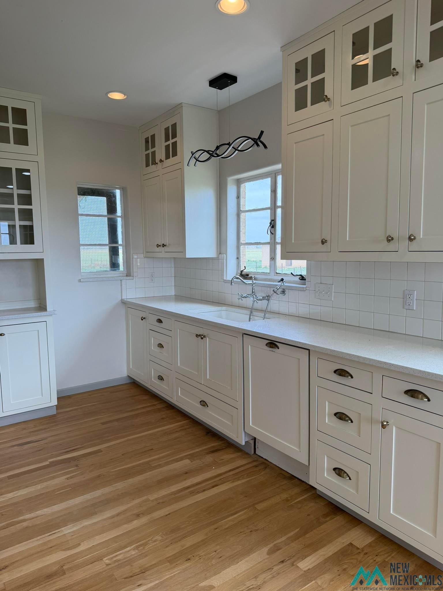 570 Curry Road North Clovis, NM 88101 - Photo 50 of 59 Kitchen featuring extensive white cabinetry with varied door styles, light-toned countertops, and light wood-finish flooring