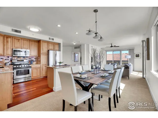 a kitchen with stainless steel appliances granite countertop a stove a sink and a refrigerator with wooden floors