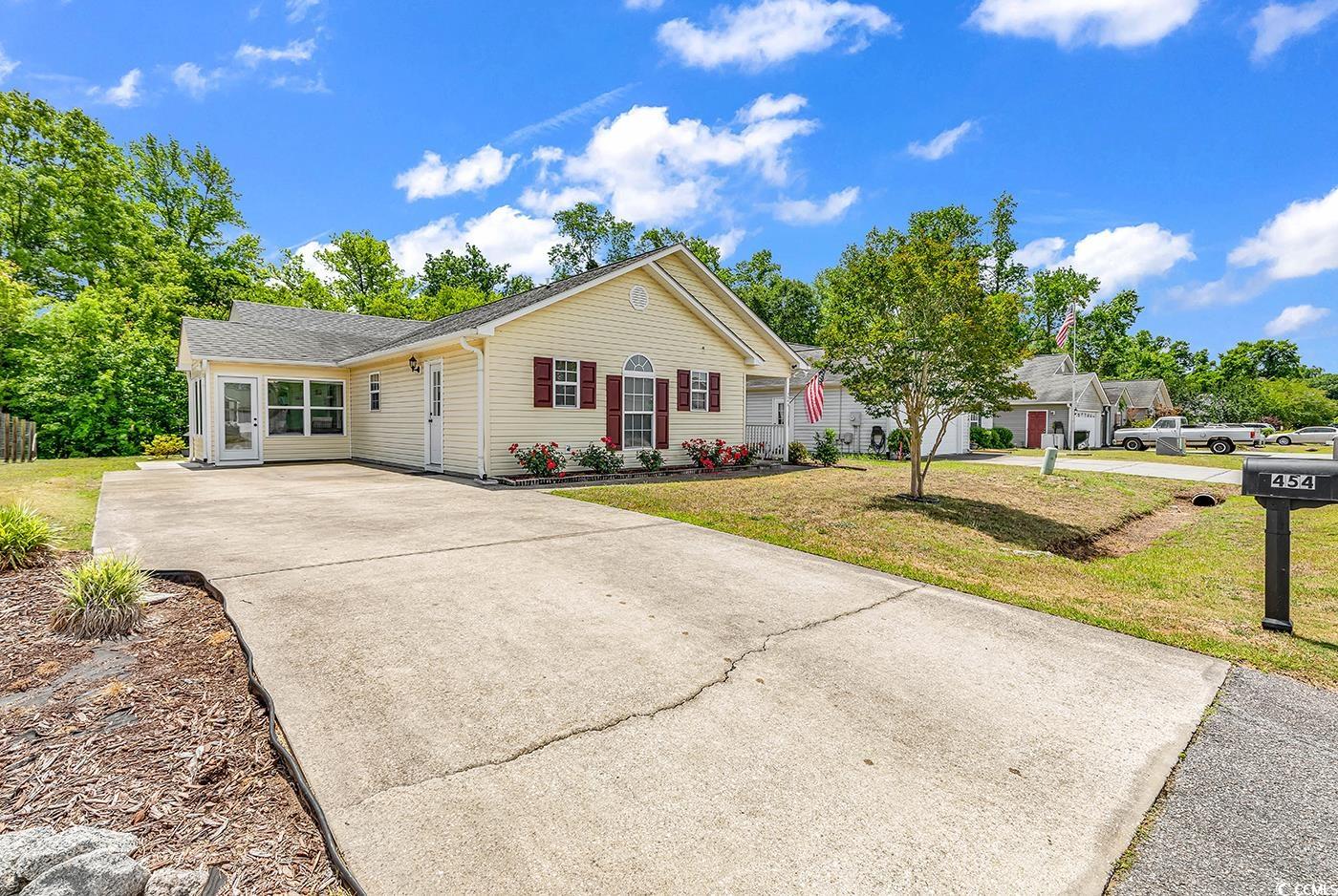 Single story home featuring concrete driveway, a front yard, and roof with shingles