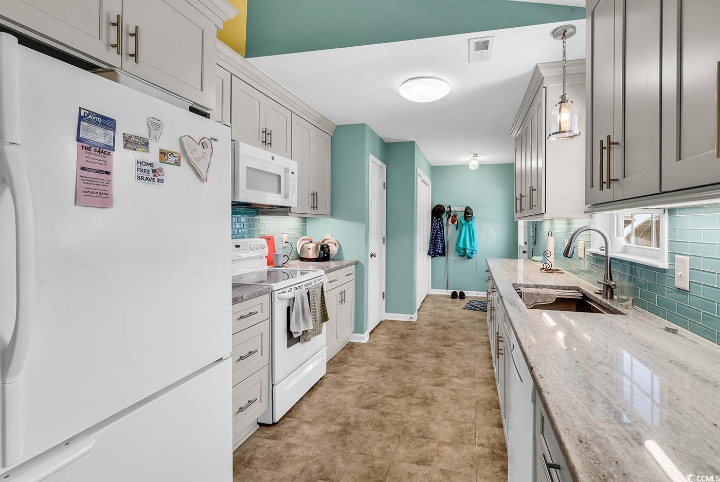 454 Sean River Road Conway, SC 29526 - Photo 4 of 38 Kitchen with white appliances, a sink, backsplash, hanging light fixtures, and light stone countertops