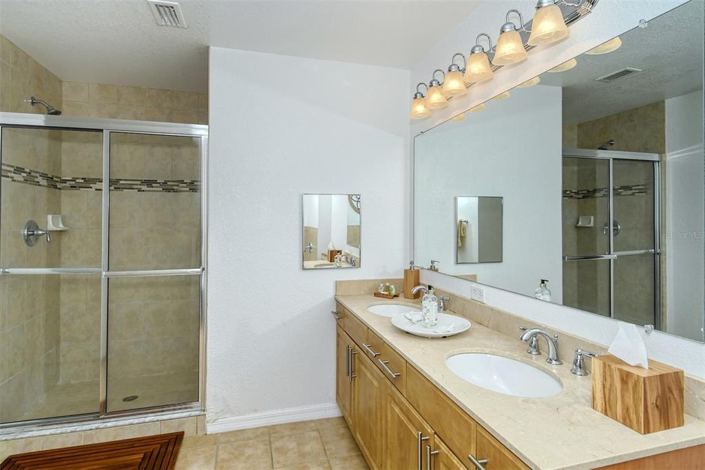 1064 North Tamiami Trail, Unit 1627 Sarasota, FL 34236 - Photo 24 of 97 a bathroom with a granite countertop sink mirror and a shower