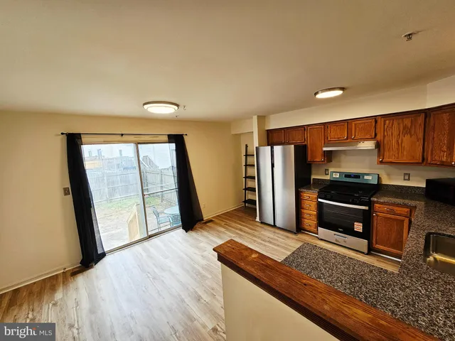 a kitchen with granite countertop a refrigerator and a stove top oven