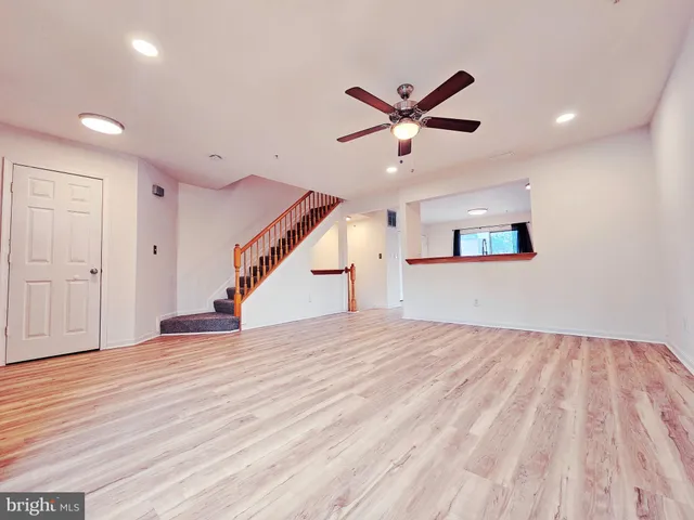 a view of an empty room with wooden floor and a ceiling fan