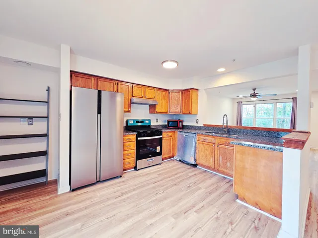a large kitchen with stainless steel appliances kitchen island granite countertop a refrigerator and a stove top oven