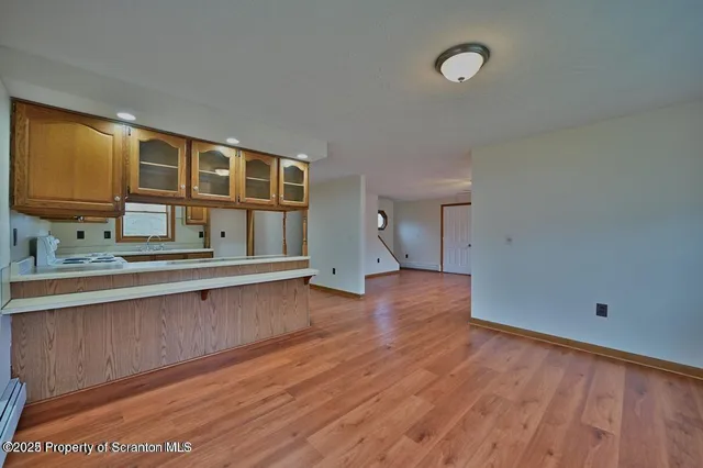 a view of an empty room with window and wooden floor
