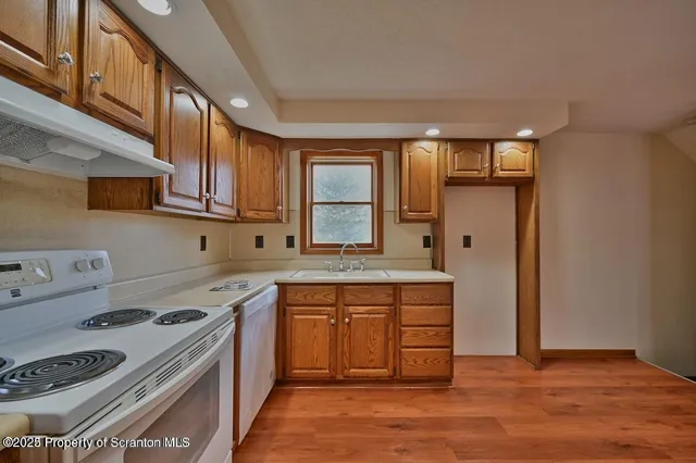 a kitchen with stainless steel appliances granite countertop a stove a sink dishwasher and a refrigerator with wooden cabinets