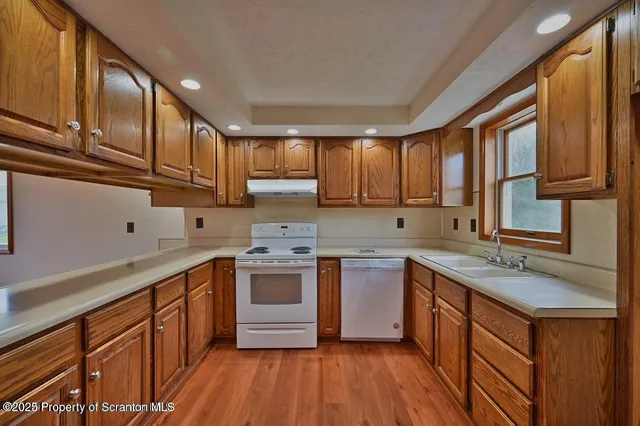 a kitchen with stainless steel appliances granite countertop wooden cabinets a sink dishwasher a stove and a refrigerator with wooden cabinets