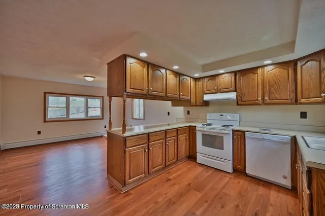 a kitchen with stainless steel appliances granite countertop wooden cabinets a sink and dishwasher a stove with wooden floors