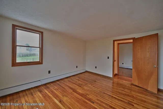 a view of an empty room with wooden floor and closet
