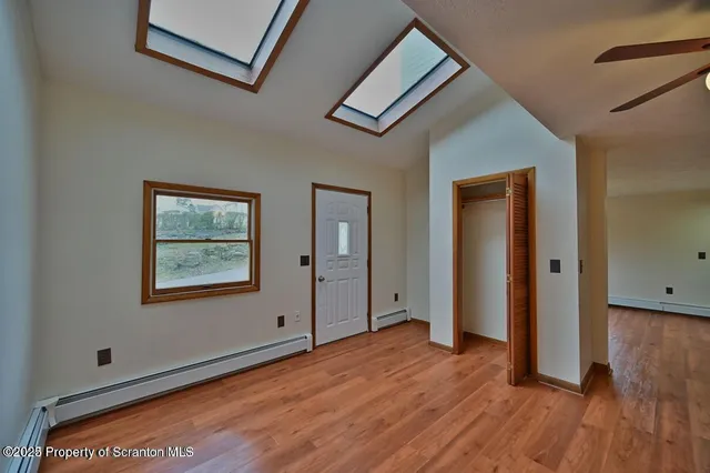 a view of an empty room with wooden floor and a window