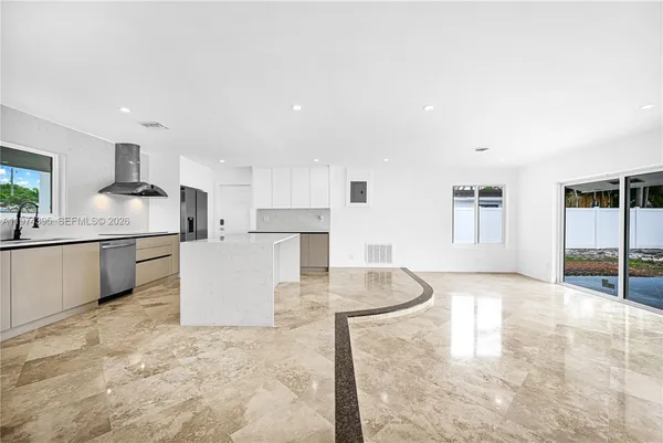 a large kitchen with kitchen island a sink a stove a refrigerator with white cabinets and wooden floor