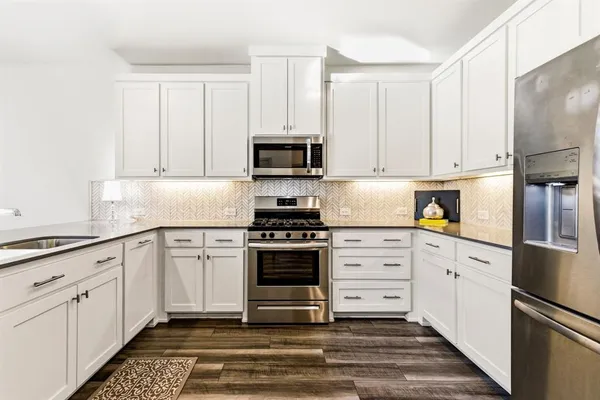 a kitchen with granite countertop white cabinets and stainless steel appliances