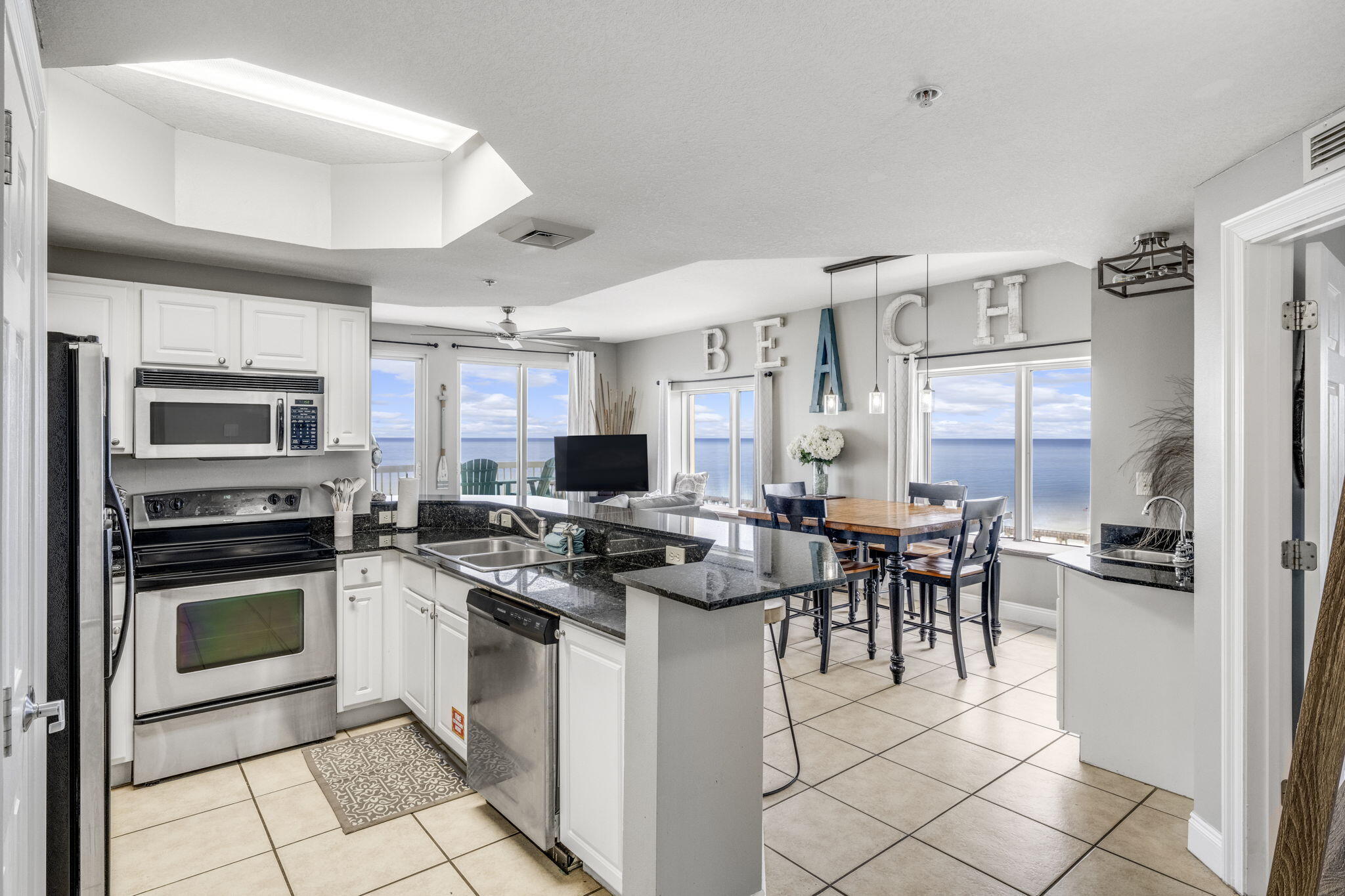 15817 Front Beach Road, Unit 21409 Panama City Beach, FL 32413 - Photo 7 of 23 a kitchen with stainless steel appliances granite countertop a stove top oven a sink dishwasher a dining table and chairs with wooden floor