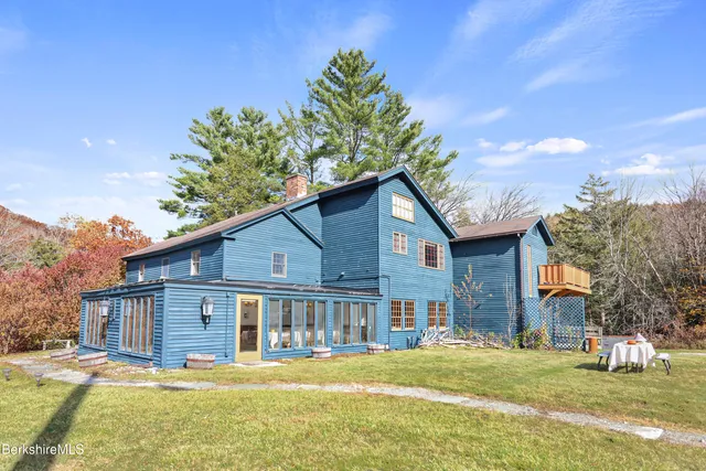 a yellow house with a big yard plants and big trees