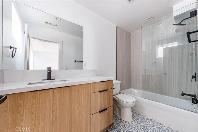 a bathroom with a granite countertop sink toilet a mirror and shower