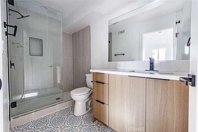 a bathroom with a granite countertop sink a toilet a mirror and shower