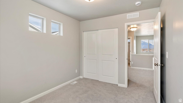 82 Provo River Road, Unit 251 Saratoga Springs, UT 84045 - Photo 26 of 32 Carpeted room with high-set windows, white baseboards, and a double-door closet with white panels