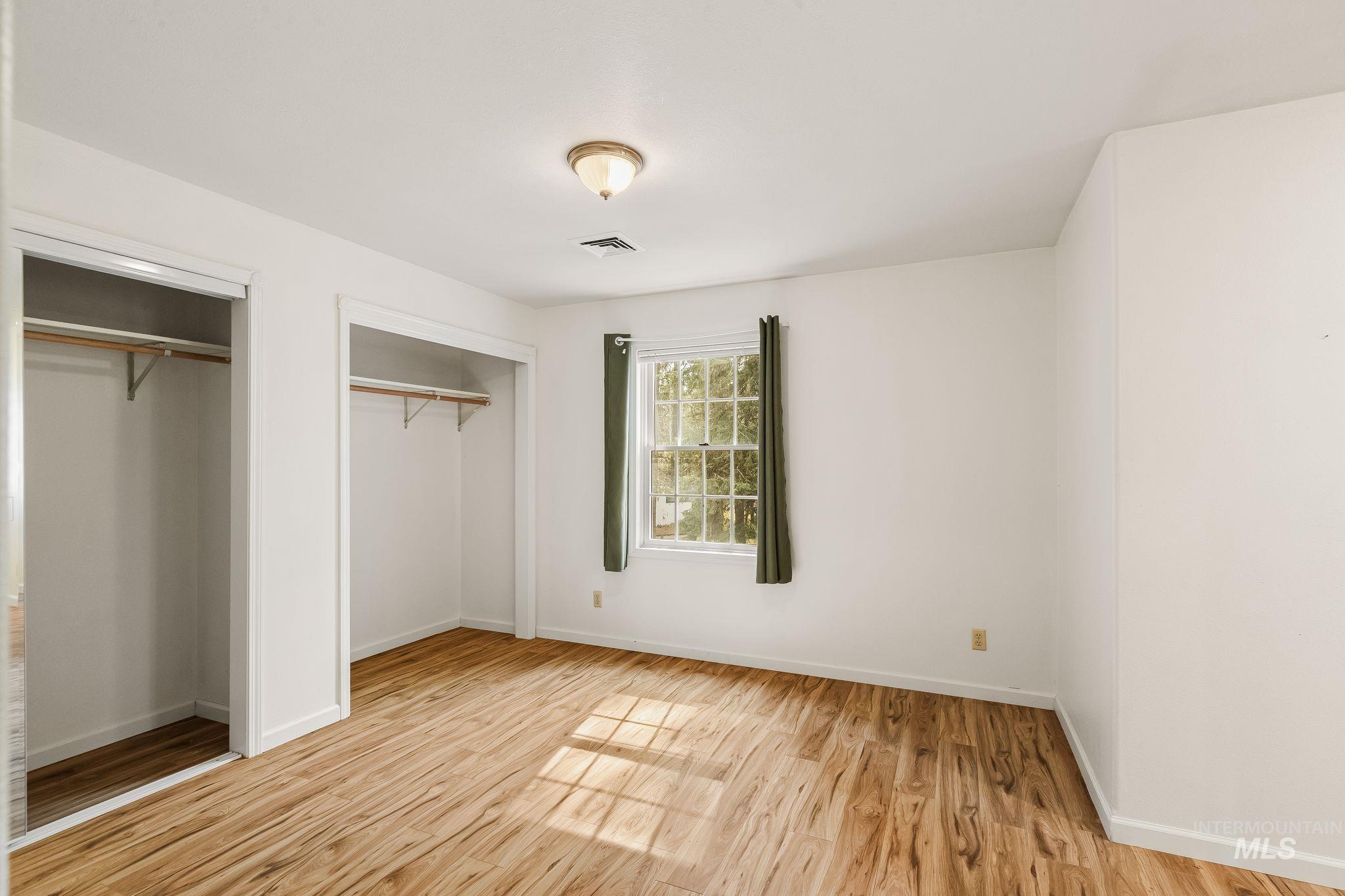 1820 Winchester Road Winchester, ID 83555 - Photo 26 of 50 Wood-finish flooring, two closets with hanging rods, and a window with green curtains