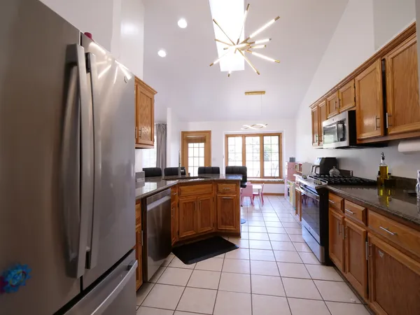 a large kitchen with stainless steel appliances granite countertop a refrigerator a sink dishwasher a stove with wooden cabinets and floor