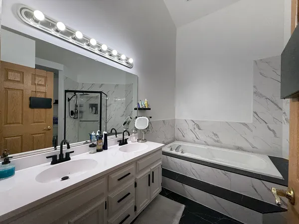a bathroom with a double vanity sink a mirror and a bathtub