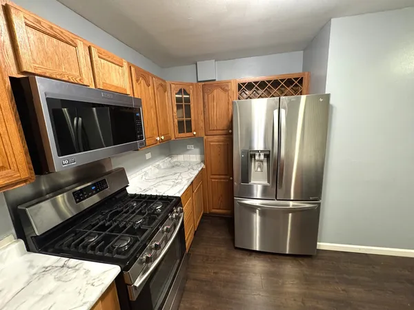 a kitchen with granite countertop a refrigerator and a stove top oven