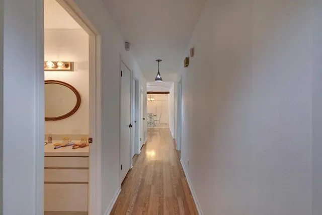 a view of a hallway with wooden floor and cabinets