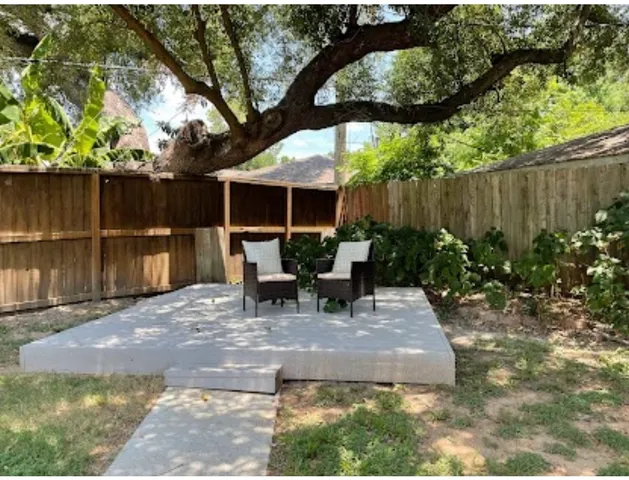 a view of backyard with table and chairs potted plants and a large tree