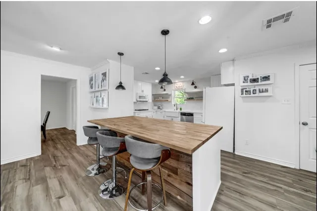a kitchen with stainless steel appliances kitchen island a wooden floor and white cabinets