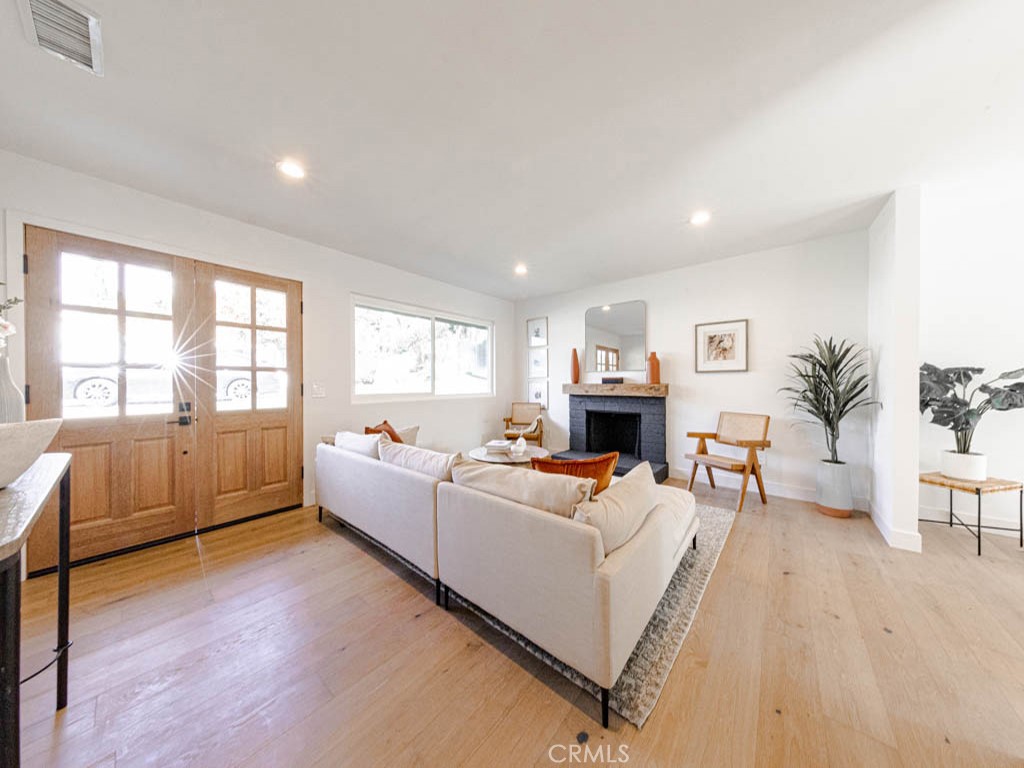 248 Crystal Lane Pasadena, CA 91103 - Photo 7 of 22 a living room with furniture a fireplace a large window and a wooden floor