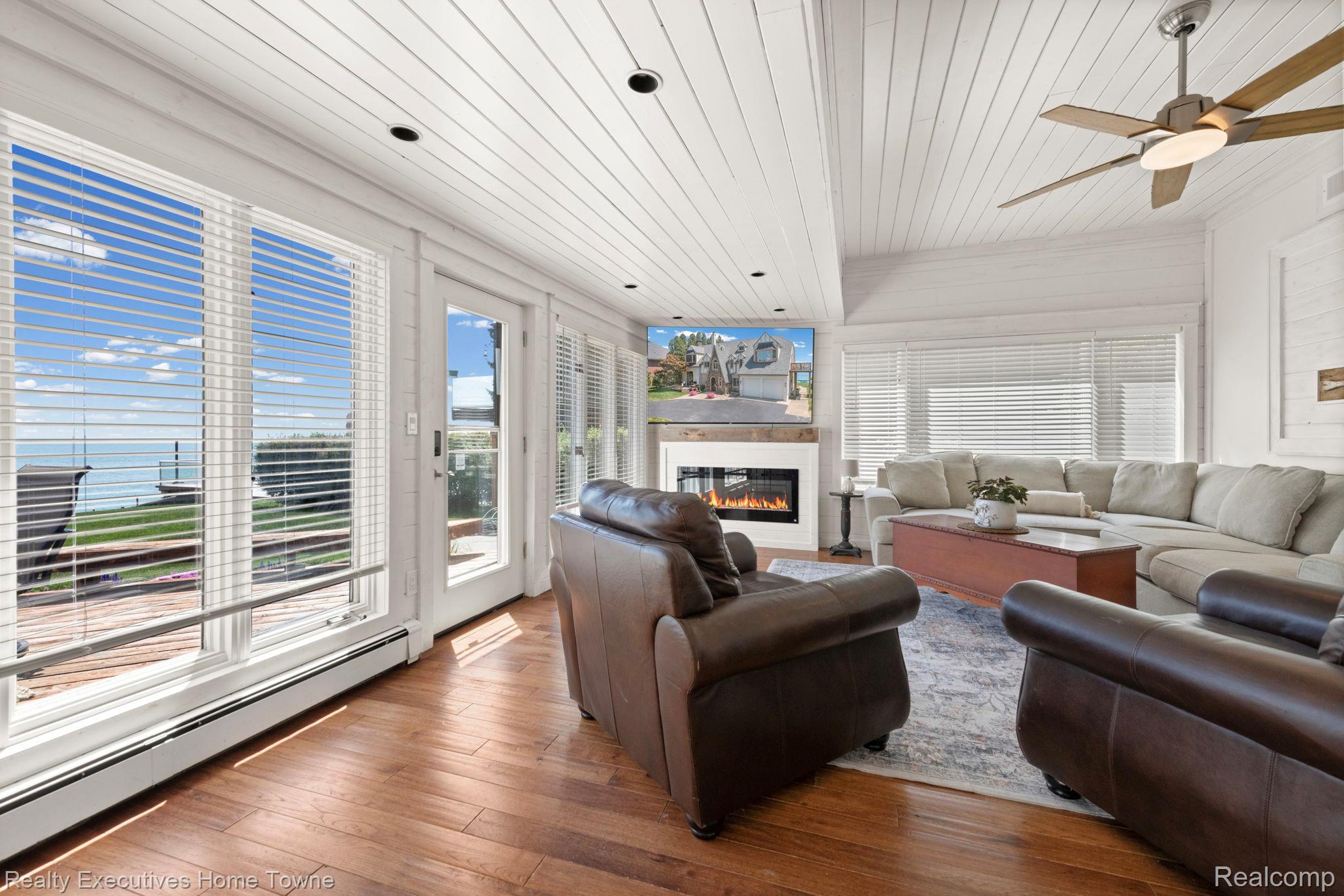 8308 Lakeshore Road Fort Gratiot, MI 48059 - Photo 48 of 79 Living room featuring expansive windows with water scenery, wood-finish flooring, a contemporary fireplace, and a vaulted plank ceiling with a ceiling fan