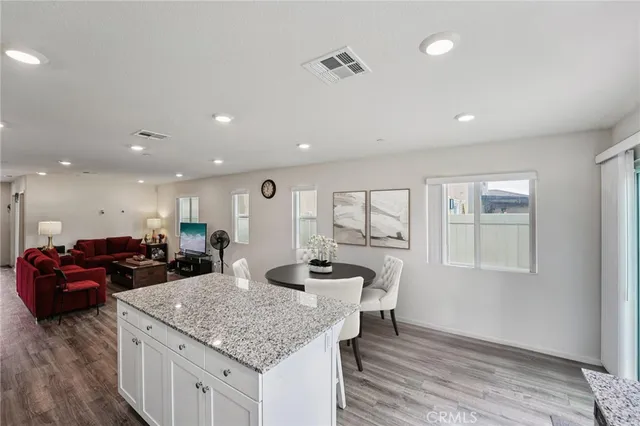 a kitchen with granite countertop kitchen island a sink dishwasher a dining table and chairs with wooden floor