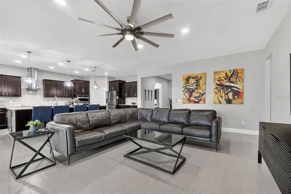 a kitchen with stainless steel appliances kitchen island granite countertop a refrigerator a stove a sink a dining table and chairs with wooden floor