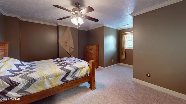 a bedroom with a bed ceiling fan and window