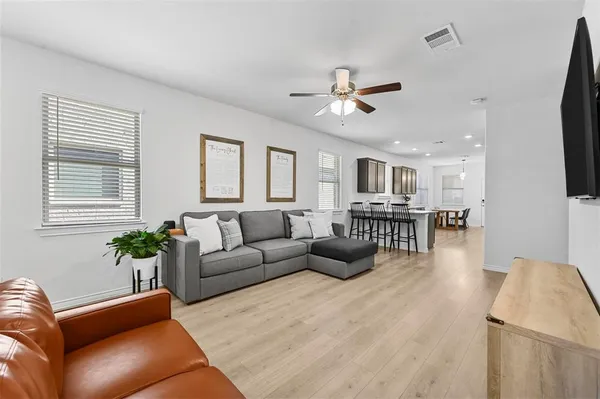 a living room with furniture kitchen view and a wooden floor