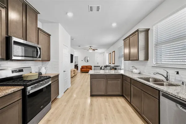 a large kitchen with stainless steel appliances granite countertop a sink dishwasher stove and oven