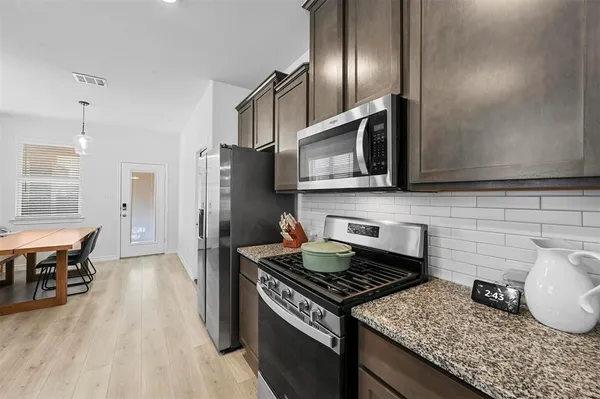 a kitchen with stainless steel appliances granite countertop a stove a refrigerator and a microwave