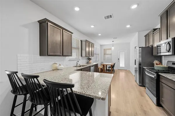 a large kitchen with granite countertop a stove a sink a counter space and dining table