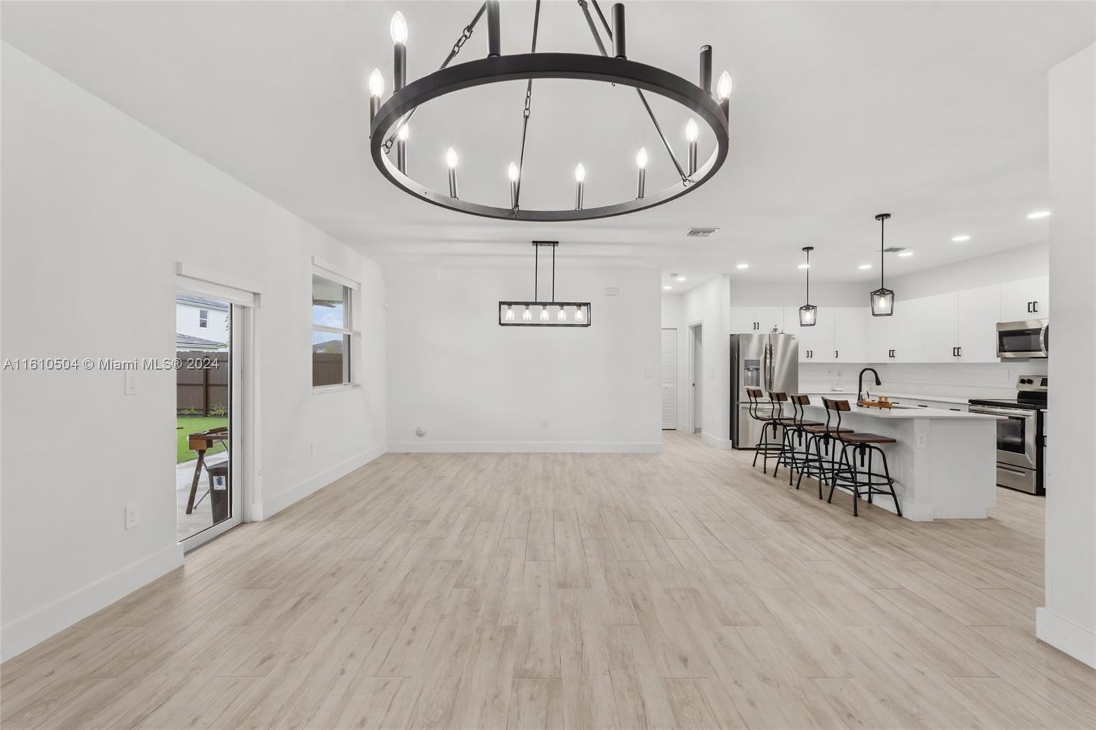 12743 Southwest 211th Street Miami, FL 33177 - Photo 16 of 38 an empty room with wooden floor and a chandelier