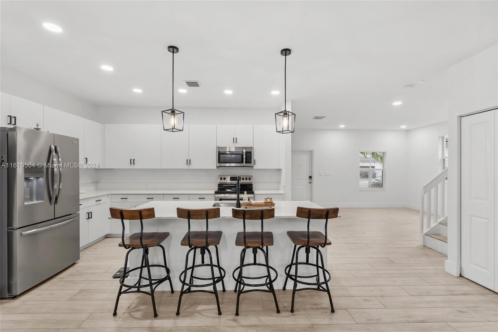 12743 Southwest 211th Street Miami, FL 33177 - Photo 9 of 38 a kitchen with stainless steel appliances kitchen island granite countertop a dining table chairs and white cabinets