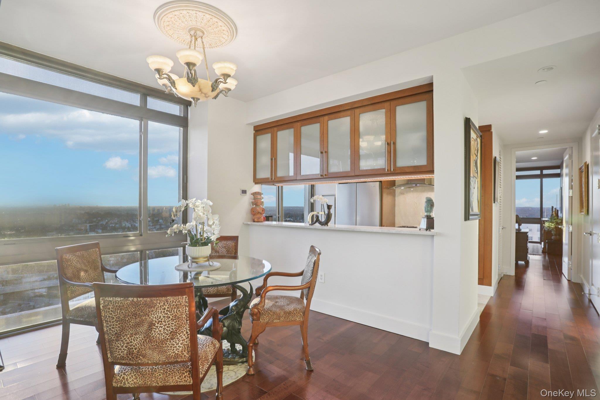 175 Huguenot Street, Unit 2403 New Rochelle, NY 10801 - Photo 12 of 30 a dining room with wooden floor a chandelier a glass table and chairs
