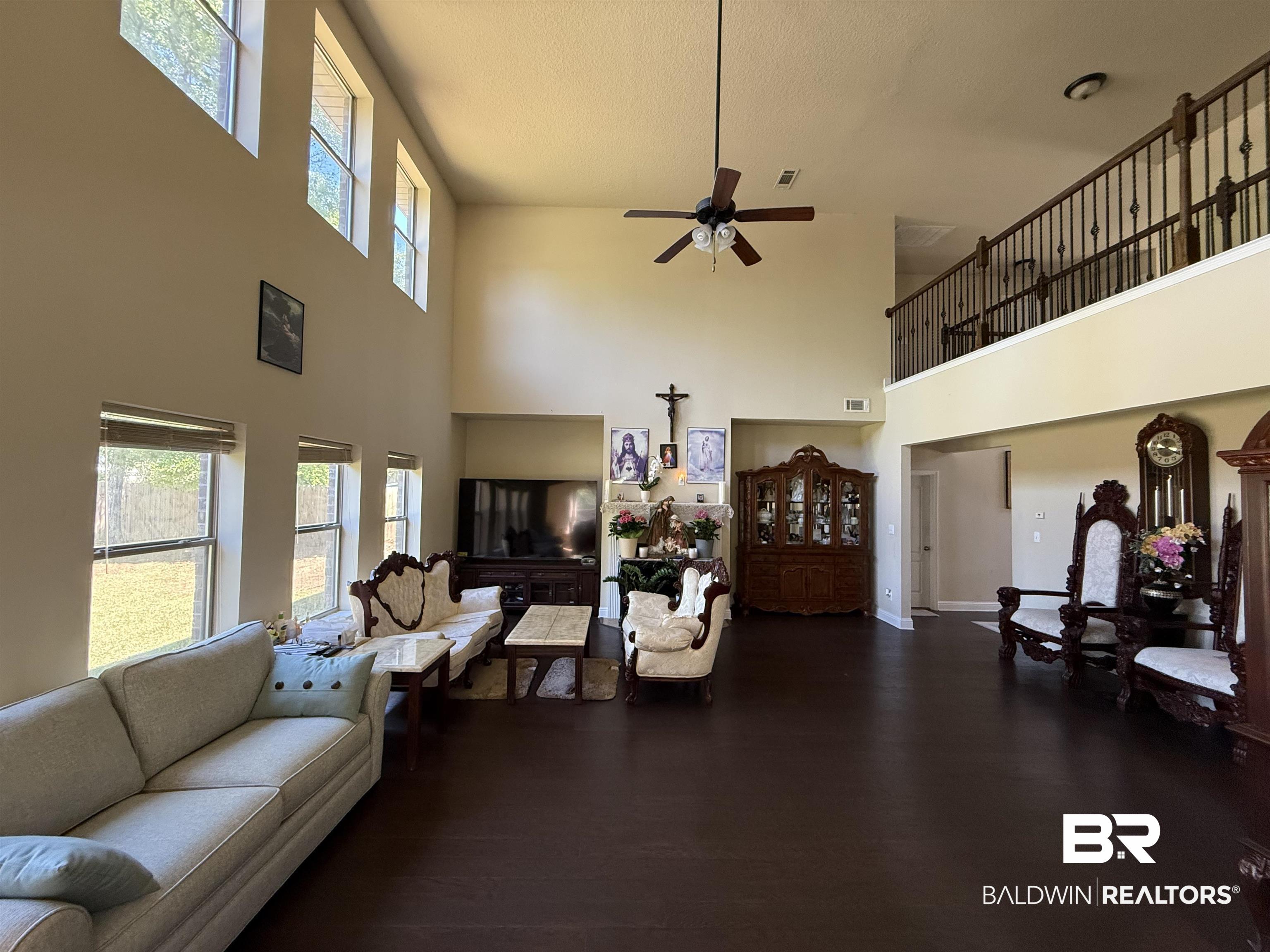 9023 Krystal Ridge Court Daphne, AL 36526 - Photo 18 of 41 Living room with ceiling fan, dark wood finished floors, a high ceiling, and a textured ceiling