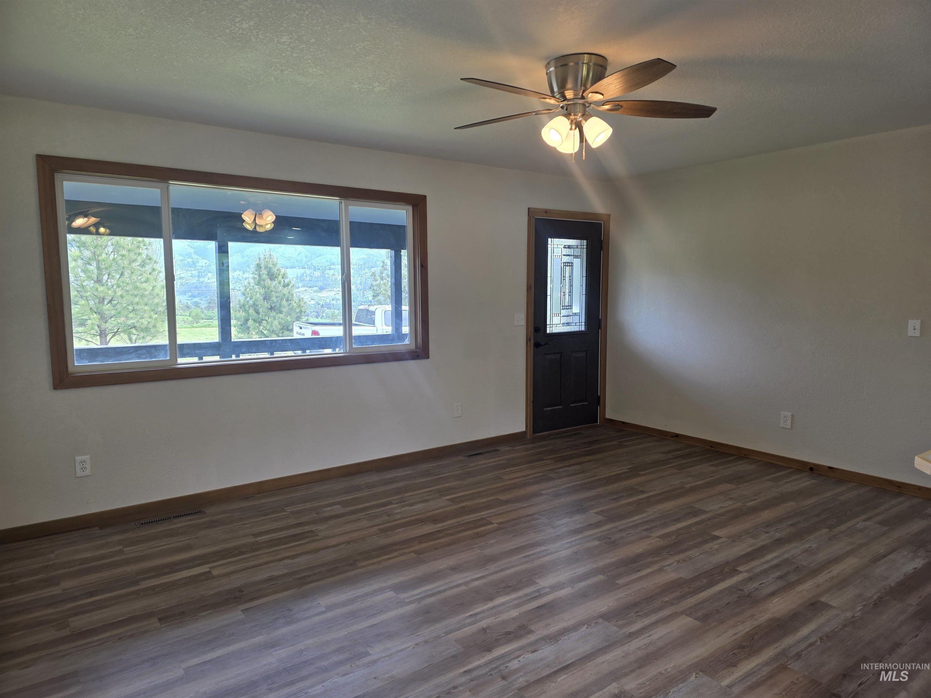 310 Fir Road Kamiah, ID 83536 - Photo 7 of 32 Spacious room with wood-finish flooring, a contemporary ceiling fan with integrated lighting, and a dark-paneled door with decorative glass inserts
