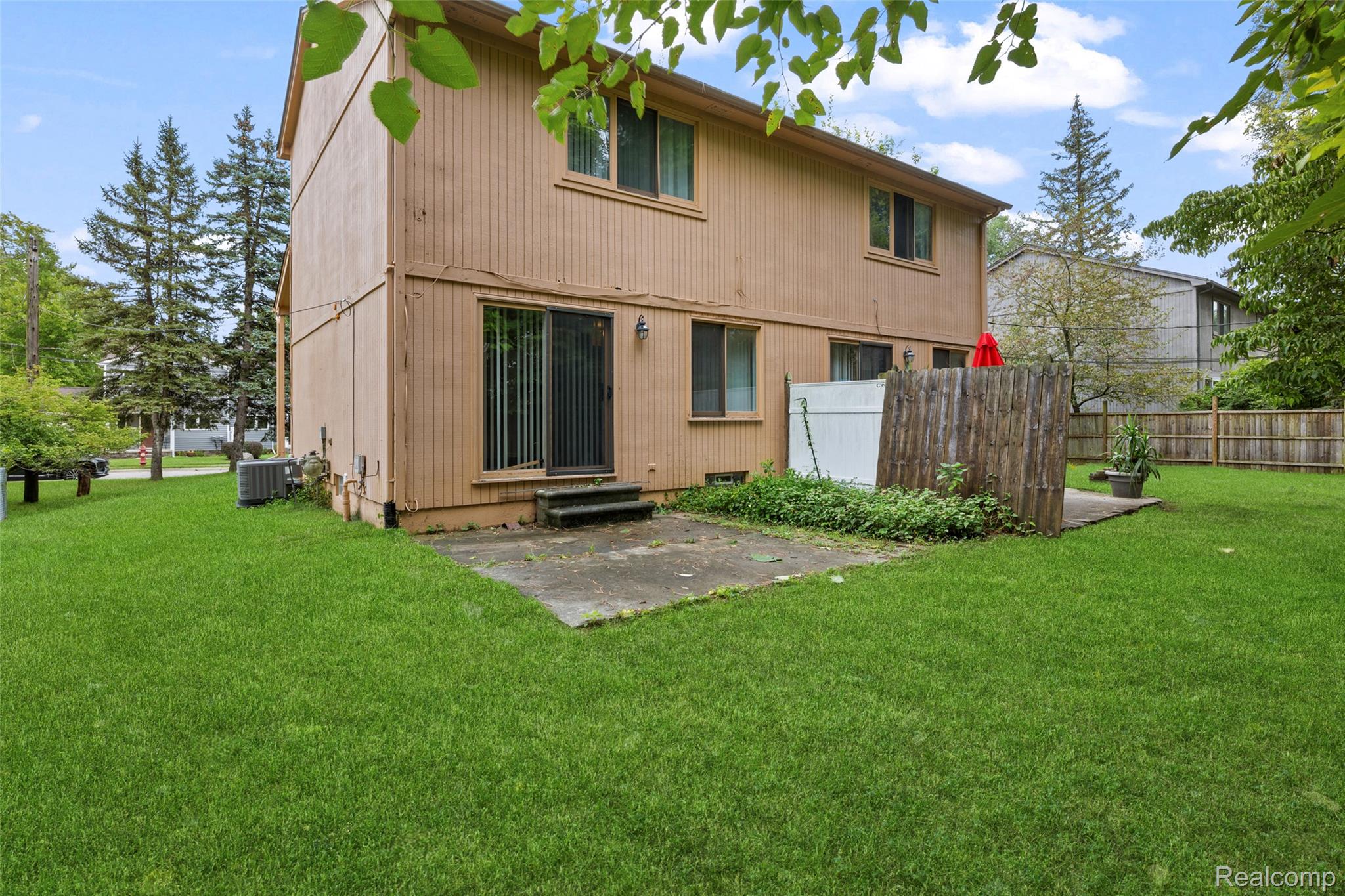 200 Fraser Street Rochester, MI 48307 - Photo 25 of 29 Rear exterior featuring a sliding glass door, an air conditioning unit, a concrete patio, and a wood privacy fence