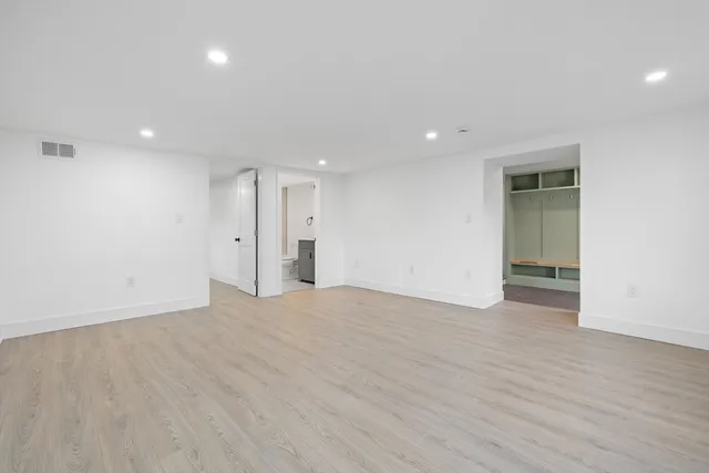 an empty room with wooden floor and natural light