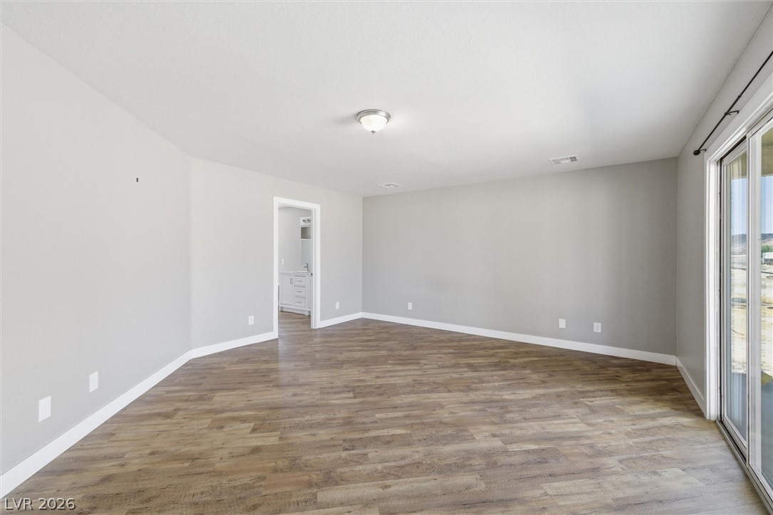 2780 West Simkins Road Pahrump, NV 89060 - Photo 23 of 40 A spacious room featuring robust wood flooring and abundant light through sliding glass doors.
